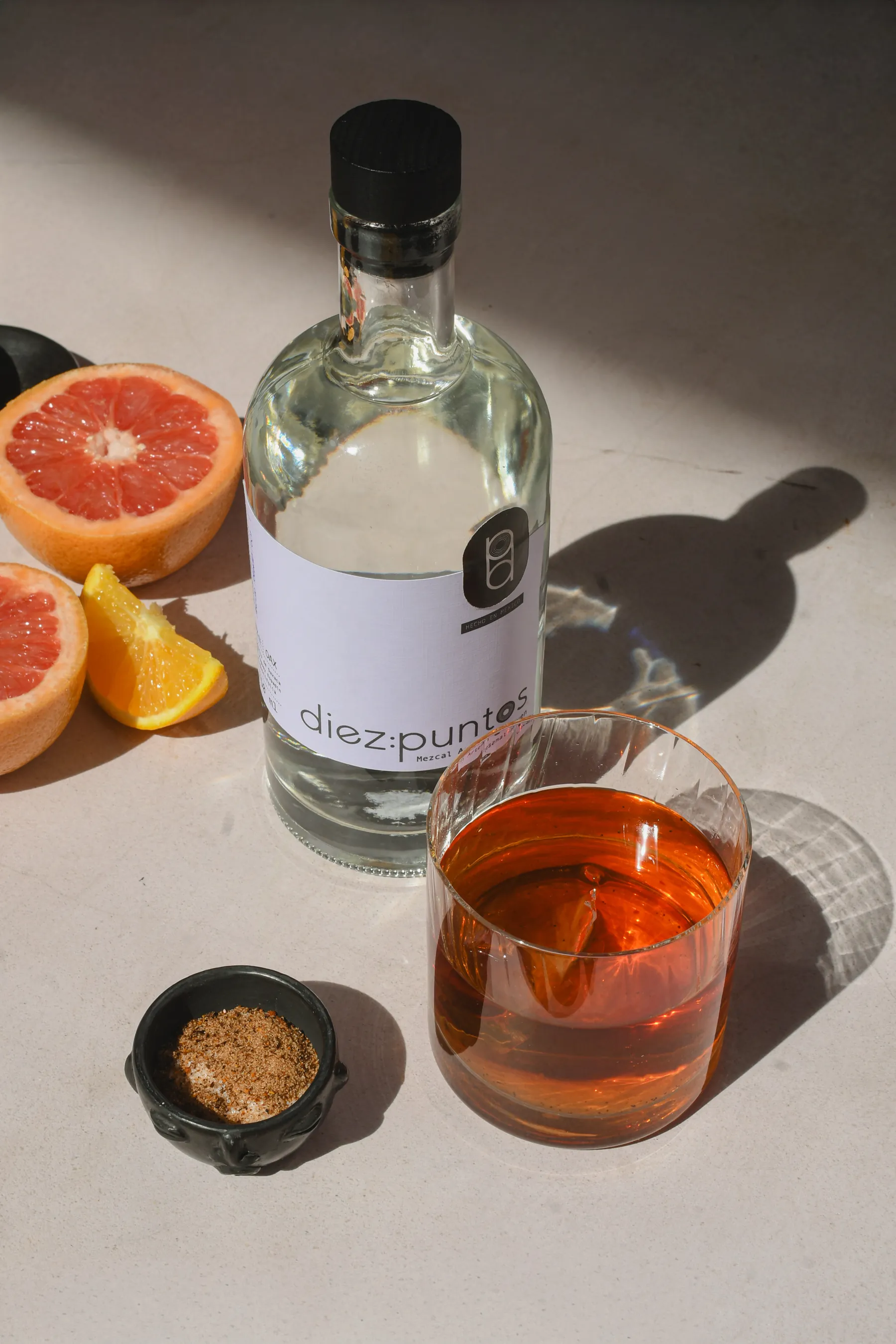 Botella de Diez Puntos servida en una mesa con naranja y coctel