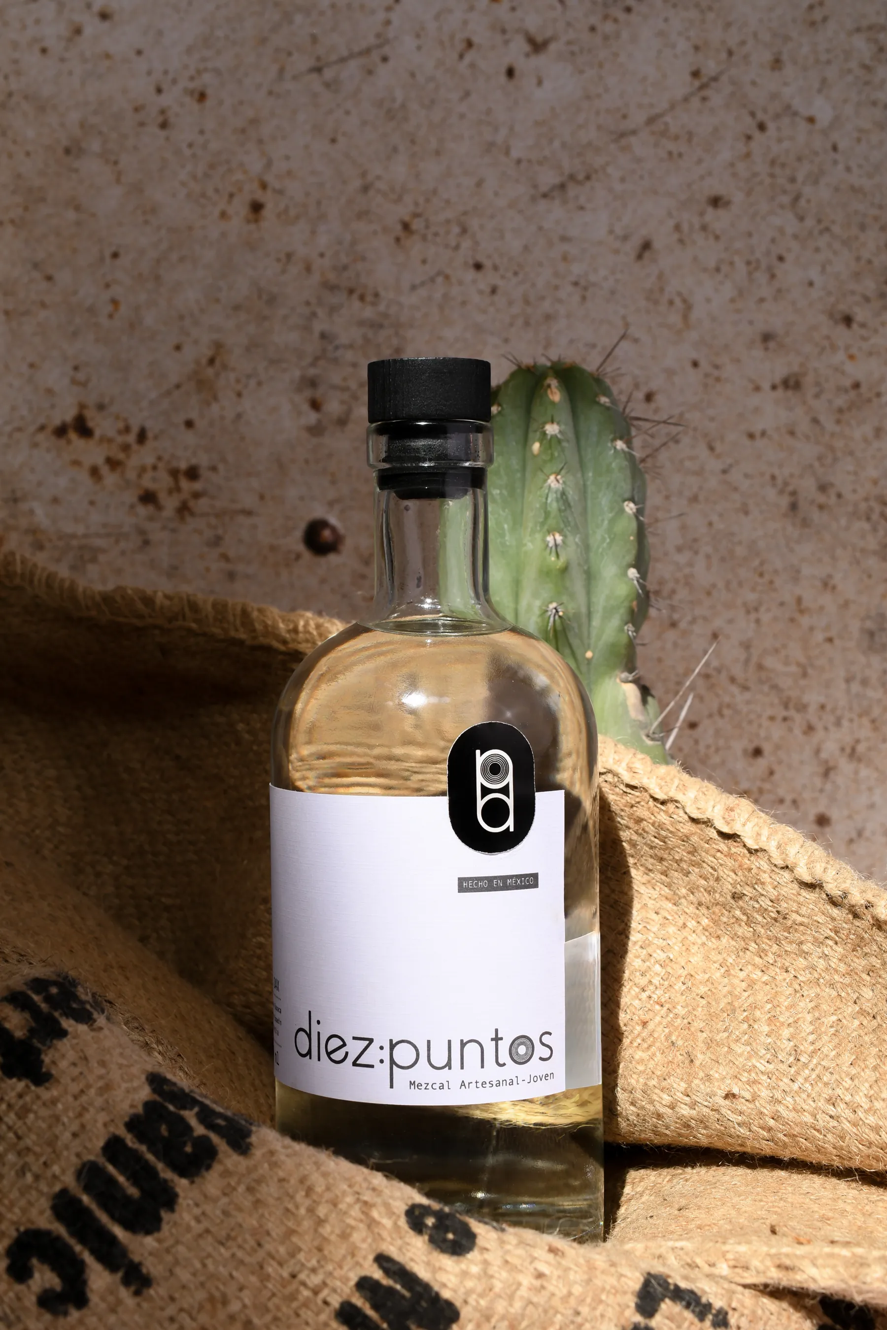 Botella de Diez Puntos sobre costal de yute con penca de agave, en Oaxaca